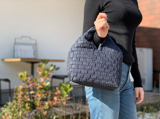 片手で持つのにバランスのいいコンパクトサイズと華美過ぎない控えめなデザイン、重厚感のある生地が、カジュアル過ぎず大人の装いに品よくマッチします。500mlのペットボトルも収まる実用性の高さや、荷物の出し入れがしやすい大きな間口が特徴。 内側にマグホックと、オープンフラットポケットが一つ付いています。 ジーンズのベルトループから着想を得たデニムプロダクトシリーズ。 倉敷市児島のジーンズ工場で生産の過程でうまれたデニム残布を縫製職人の手で紐状の生地に加工。丈夫で経年にも耐えうる紐状のデニムは、三つ折りにして縫製されているため強度があり長期使用にも耐えることができます。紐を一本一本手作業で編み込み、独特の手法で立体的に形作られていくことによって、デニム本来の柔らかな美しさを引き立てます。 今ある資源、本来廃棄される素材の再利用を最大限に目指しながらも、製品自体には傷の部分が含まれないよう細心の注意を払って製作しています。 サイズ(ONE SIZE) 本体:縦18cm× 横22cm × マチ10cm 持ち手の長さ:14cm カラー: 掲載写真はインディゴ(インディゴステッチ)です。
